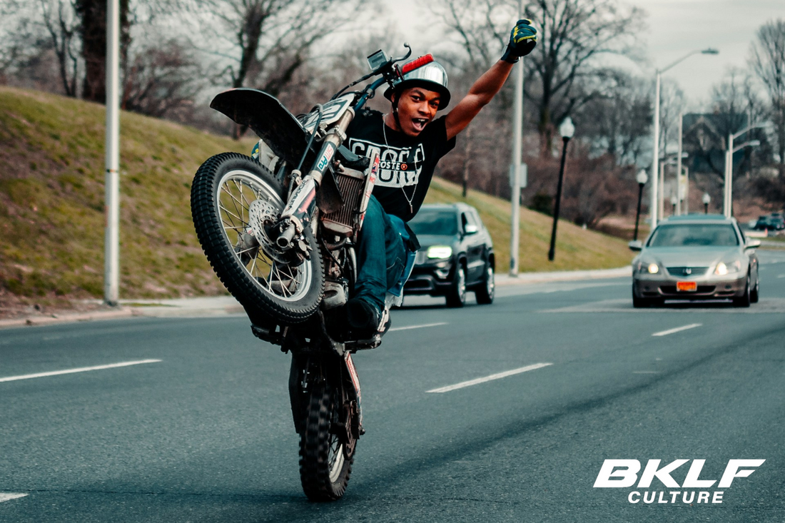 happy guy doing a wheelie on his bike